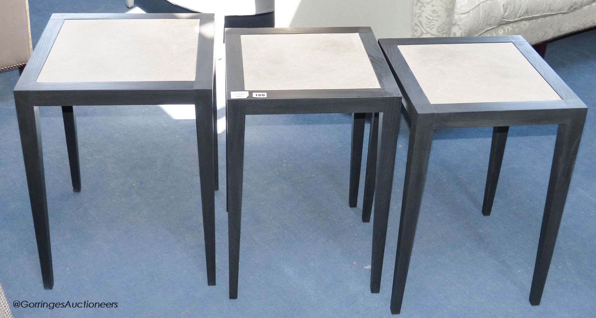 A pair of ebonised ash and parchment topped lamp tables, each 40 cm wide, 60 cm high, and a similar larger table 45 cm wide (three)